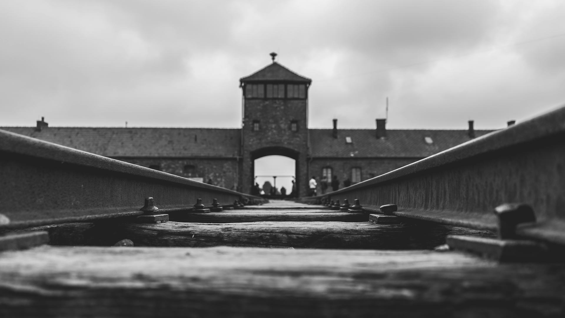 Main gate of the former Auschwitz II-Birkenau camp, now part of the Auschwitz-Birkenau Memorial, in black and white