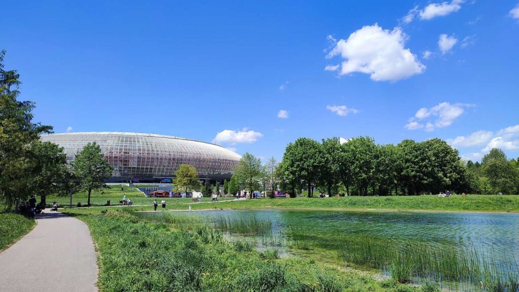 TAURON Arena Kraków i staw w Parku Lotników Polskich w słoneczny dzień